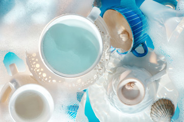 Doing dishes concept, white porcelain plates and cups with bubbles and foam