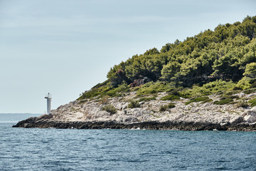 Fototapeta na wymiar Small lighthouse on the island, Stone coast, sunny weather