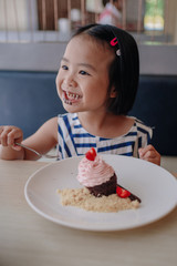 A girl eating happily with a strawberry whipped cream. 4 year old daughter Celebrating a birthday with a chocolate lava dessert