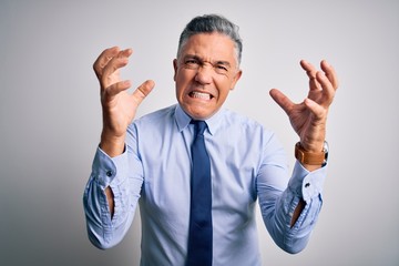 Middle age handsome grey-haired business man wearing elegant shirt and tie Shouting frustrated with rage, hands trying to strangle, yelling mad