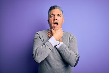 Middle age handsome grey-haired man wearing elegant sweater over purple background shouting and suffocate because painful strangle. Health problem. Asphyxiate and suicide concept.