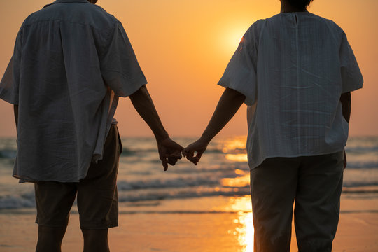 Elderly couple moments of relaxation with a happy picture impression. Tour. Portrait of a middle-aged man standing holding hands by the sea in the evening.