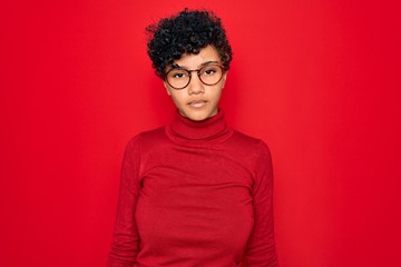 Fototapeta na wymiar Young beautiful african american afro woman wearing turtleneck sweater and glasses Relaxed with serious expression on face. Simple and natural looking at the camera.