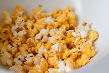 Close up of fresh made popcorn in a white bowl. Entertainment at home concept