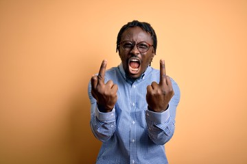Young handsome african american man wearing shirt and glasses over yellow background Showing middle...