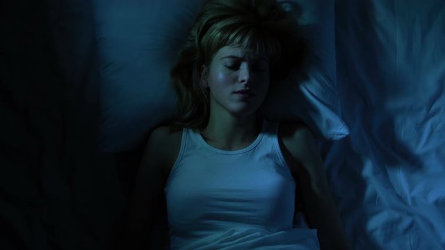 Young woman shuddering during sleep, seeing nightmares, bad sleep conditions