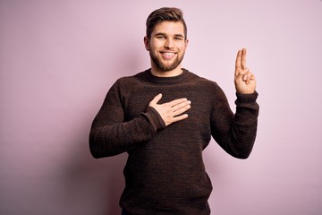 Young blond man with beard and blue eyes wearing casual sweater over pink background smiling...