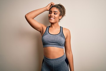 Young african american sportswoman doing sport wearing sportswear over white background smiling confident touching hair with hand up gesture, posing attractive and fashionable