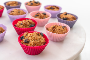 Bran muffins with dry cranberries close up in baking silicon cups on white background. Healthy food, good source of dietary fiber