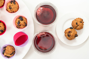 Bran muffins with dry cranberries, and cups of hibiscus tea close up on white background. Healthy food, good source of dietary fiber