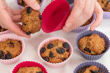 Bran muffins with dry cranberries close up in baking silicon cups on white background. Healthy food, good source of dietary fiber