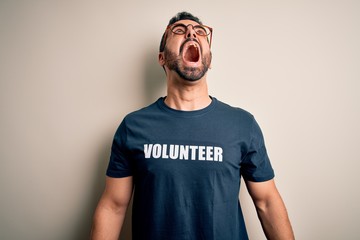 Handsome man with beard wearing t-shirt with volunteer message over white background angry and mad...