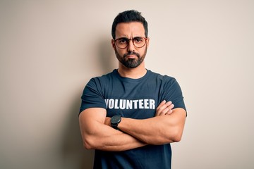 Handsome man with beard wearing t-shirt with volunteer message over white background skeptic and nervous, disapproving expression on face with crossed arms. Negative person.