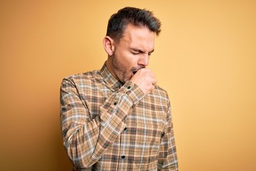 Fototapeta premium Young handsome man wearing casual shirt standing over isolated yellow background feeling unwell and coughing as symptom for cold or bronchitis. Health care concept.