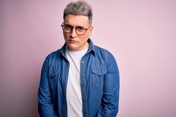 Young handsome modern man wearing glasses and denim jacket over pink isolated background skeptic and nervous, frowning upset because of problem. Negative person.