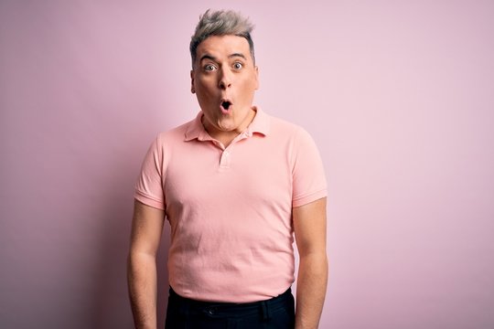 Young handsome modern man wearing casual pink t-shirt over isolated background afraid and shocked with surprise expression, fear and excited face.