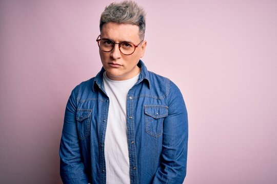 Young handsome modern man wearing glasses and denim jacket over pink isolated background skeptic and nervous, frowning upset because of problem. Negative person.