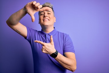 Young handsome modern man wearing casual purple t-shirt over isolated background smiling making frame with hands and fingers with happy face. Creativity and photography concept.