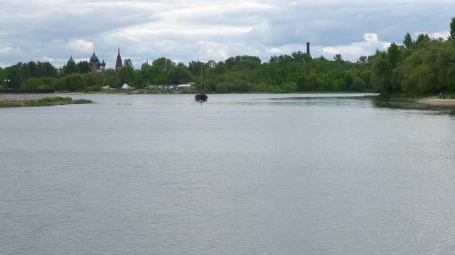 An old style Russian wind boat crossing the Kotorosl river with Church of St. John Chrysostom in Background