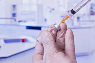 gloved hands manipulating a syringe with medications - macro