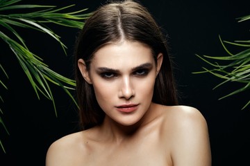 Beautiful woman bare shoulders clean skin green leaves.