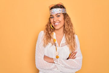 Naklejka premium Young beautiful blonde hippie woman with blue eyes wearing sunglasses and accessories happy face smiling with crossed arms looking at the camera. Positive person.