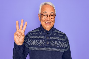 Middle age senior grey-haired man wearing glasses and winter sweater over purple background showing...