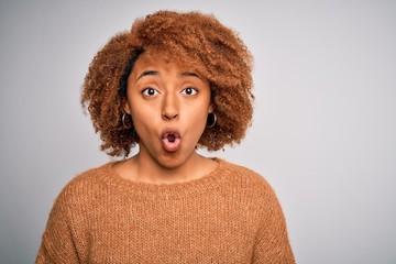 Young beautiful African American afro woman with curly hair wearing casual sweater scared in shock with a surprise face, afraid and excited with fear expression