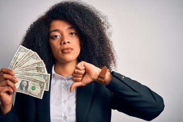 Young african american business woman with afro hair holding cash dollars banknotes with angry...