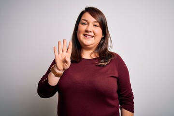 Beautiful brunette plus size woman wearing casual sweater over isolated white background showing and pointing up with fingers number four while smiling confident and happy.