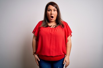 Beautiful brunette plus size woman wearing casual red t-shirt over isolated white background afraid and shocked with surprise and amazed expression, fear and excited face.