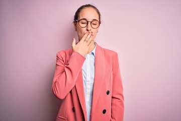 Young beautiful businesswoman wearing jacket and glasses over isolated pink background bored...