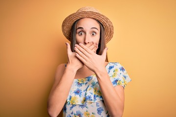 Young beautiful woman wearing casual t-shirt and summer hat over isolated yellow background shocked covering mouth with hands for mistake. Secret concept.