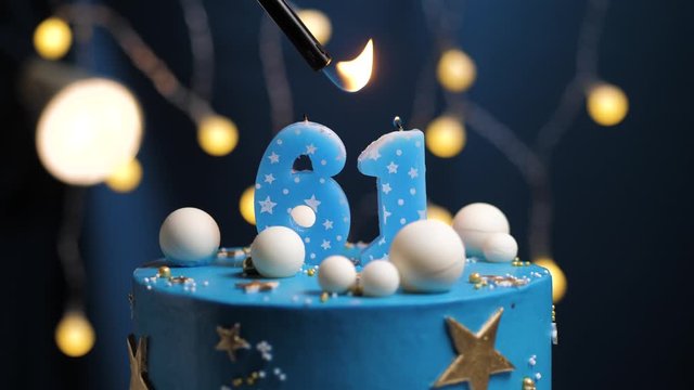 Birthday cake number 61 stars sky and moon concept, blue candle is fire by lighter and then blows out. Copy space on right side of screen if required. Close-up and slow motion
