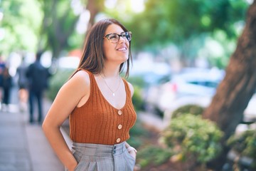 Young beautiful woman smiling happy and confident. Standing with smile on face at the town street