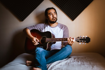 Obraz premium Joven adulto solo en casa tocando la guitarra música