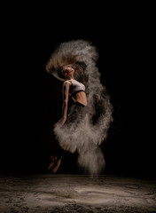 Young woman jumping in dust cloud shot