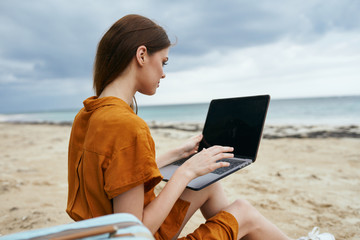 young woman with laptop on the beach