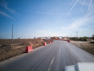 autopista de cemento en reparación, con próxima desviación y puente en construcción al final.