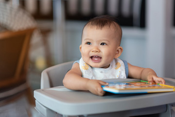 Asian pretty lovely baby girl with her colorul reading book and  smile laughing action
