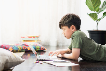 Smart looking Asian preteen boy use laptop computer at home study lessons through online learning...