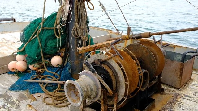 Fishermen at work. Sailors pull the trawl with the catch onto the deck of the seiner. Caught fish inside the net. Fishing tackle. Black Sea. Mainly cloudy.