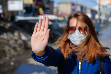 A woman in a medical mask walks alone on the street during the quarantine. Portrait of a female in...
