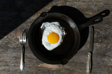 Fried egg in a cast-iron skillet. Simple breakfast. Minimalism.  Hard light photo.