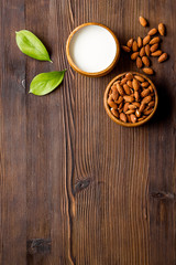 Almond milk near nuts on wooden background top-down copy space