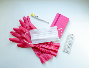 Quarantine set. Pink gloves and a notebook, mask, thermometer. pills on a white background. Flat lay