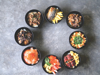 Various Japanese food in a bowl arranged in a circle on the cement floor background