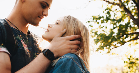 Close photo of strong caucasian man embracing his girlfriend and looking in her eyes