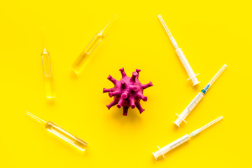 Corona virus Covid-19 - vaccine concept with syringe - on yellow background top-down