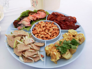 Cashews, dumplings, crispy pork, pork sausage salad and Century eggs in an appetizer white backdrop